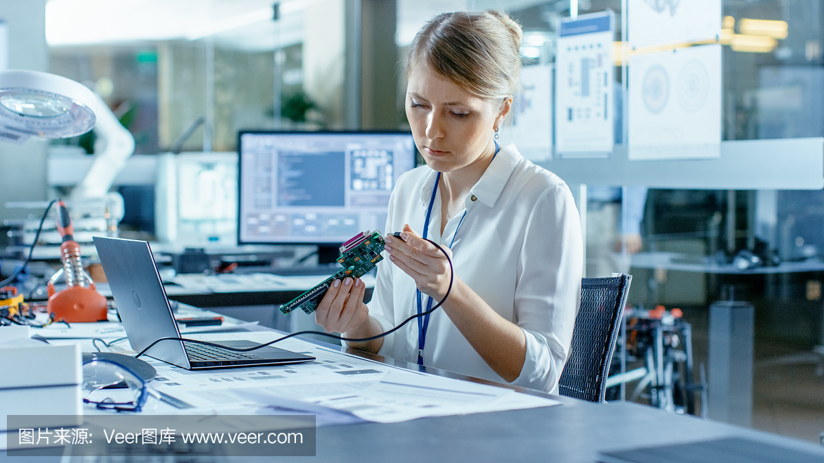 女計算機科學(xué)家將電路板連接到她的筆記本電腦并開始編程。她在先進技術(shù)實驗室工作。